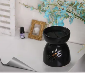 Detalle del quemador de cera de cerámica negro mate con diseño de hoja en ambiente