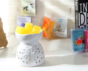 Detail shot of white ceramic wax melt burner with yellow scented wax cubes on top.