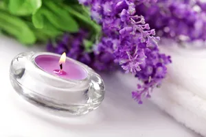 Glazen tealight kaars met paarse was, elegante lavendelbloem en handdoek decoratie voor ontspannende sfeer.