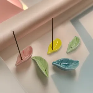 Detalle de mini quemador de incienso de cerámica con forma de hoja y superficie suave.