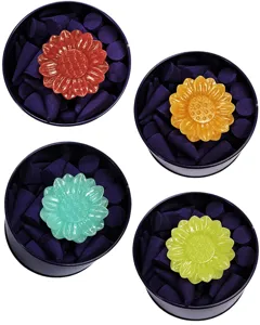 Set of colorful resin sunflower incense holders with deep purple incense cones in black tins