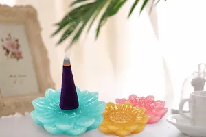 Close-up detail of a burning purple incense cone on a blue lotus holder with smoke