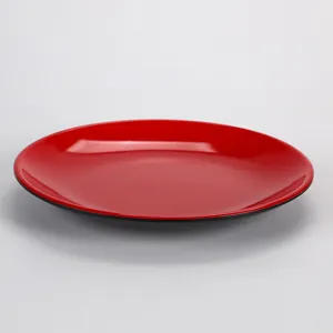 Vue latérale d'une assiette ronde en mélamine brillante rouge et noire pour la restauration