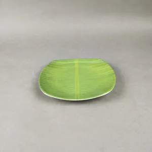 Détail d'assiette en mélamine feuille de bananier avec texture verte réaliste et bord lisse.