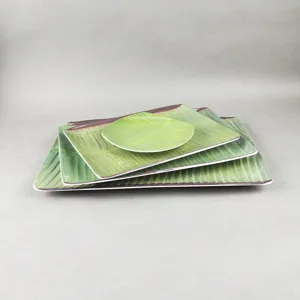 Gros plan detail d'assiettes en melamine en forme de feuille de bananier sur fond.