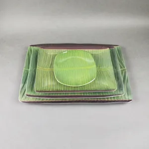 Vue détaillée d'assiettes en mélamine en forme de feuille de bananier, texture réaliste.