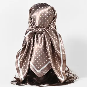 Satin silk-like square scarf featuring white polka dots worn as a stylish headscarf