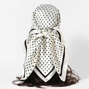 Back view of a white satin square scarf with black polka dots tied on a hair prop