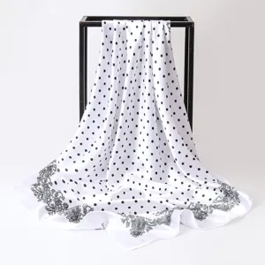 Detailed view of a white satin square scarf with black polka dots and paisley border.