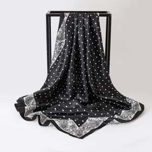 Close-up of 90cm black and white polka dot satin scarf with paisley pattern border