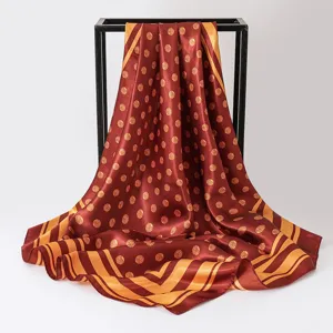Detailed view of elegant burgundy silk-like square scarf with stylish gold polka dots