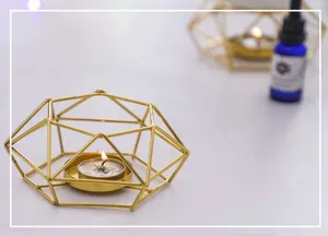 Gold geometric metal candle holder detail view, minimalist modern home decor style ornament.