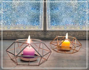 Close-up detail of geometric metal candle holders with glowing candles in cozy room.