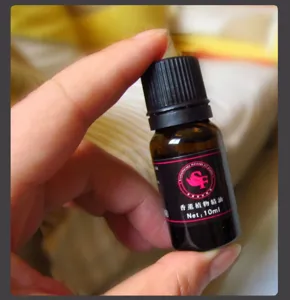 Mano sosteniendo un frasco de vidrio ámbar de 10 ml de aceite esencial para difusor