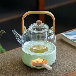 Glass teapot and ceramic tea warmer with wood handle for cozy home tea time and brewing.