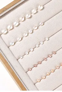 Macro detail showing natural white and pink rice-shaped freshwater pearls on a velvet tray