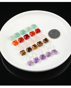 Assorted natural stone four-leaf clover beads displayed on a white tray for DIY