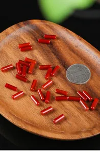 Close-up of natural red agate cylinder beads on a wooden tray for DIY jewelry