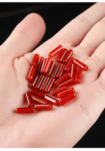 Natural red agate cylinder beads shown in hand for size scale and texture detail