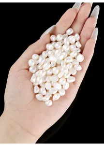 Macro detail view of natural white rice-shaped freshwater pearl beads held in hand