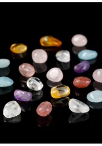 Primo piano di varie pietre naturali burattate per gioielli fai-da-te come quarzo rosa.