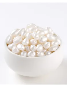 Macro view of white natural freshwater pearls with drill holes in a white ceramic bowl