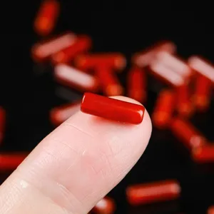 Single natural red agate cylinder bead shown on a fingertip for DIY jewelry making