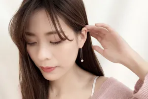 Detailed view of elegant ginkgo leaf long thread earrings worn by an Asian model