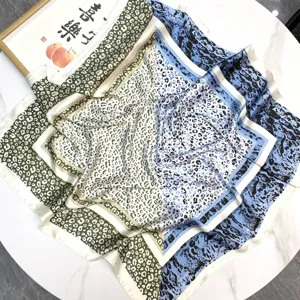 Detailed view of a leopard print square silk scarf with blue and beige patterns.