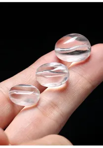 Primer plano de cuentas de cuarzo transparente ovaladas con alta transparencia y brillo.