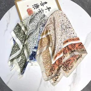 Close-up detail showing various color leopard print silk square scarves on marble