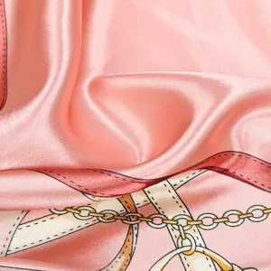 Texture détaillée du foulard en soie rose avec des motifs élégants de chaînes dorées
