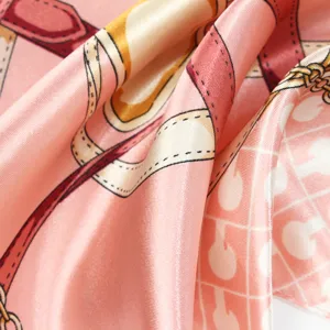 Vue macro d'un foulard en soie rose avec sangles de chaîne et motifs monogrammes