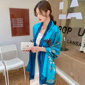 Elegante sciarpa in seta blu con stampa floreale indossata da una modella al bar