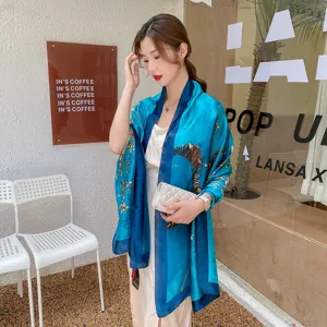Elegante scialle in seta blu con stampa floreale tradizionale indossato da una modella al bar