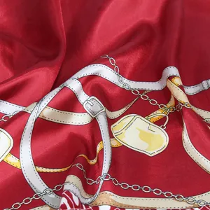 Gros plan d'un foulard en satin rouge avec des motifs de chaînes et de ceintures.