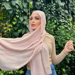 Modell trägt einen strukturierten hellrosa Baumwoll-Leinen-Hijab vor grünem Hintergrund