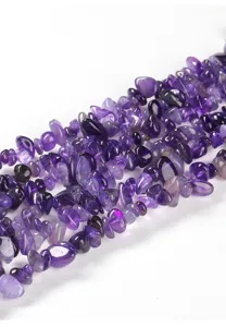Vista macro di perle di ametista naturale viola per la creazione di gioielli fai da te.