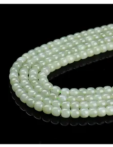 Macro detail of high-quality natural pale green Hetian jade beads with a smooth finish.