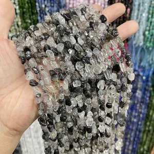 Macro detail of 6-8mm natural black rutilated quartz irregular tumbled gemstone beads