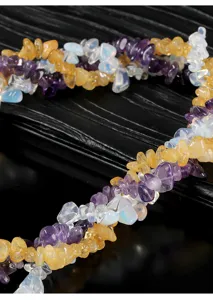 Primer plano de cuentas de trozos de cristal natural en colores púrpura, amarillo y blanco.