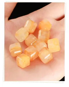 Close-up of translucent natural yellow phantom quartz sugar cube beads in a palm