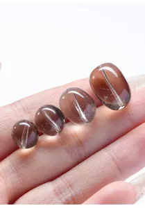 Cuentas ovaladas planas de cuarzo ahumado natural para joyería DIY mostradas en mano