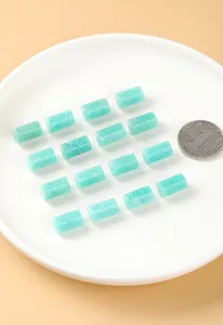 Close-up of natural Amazonite hexagonal cylinder beads on a white plate with a coin for scale.