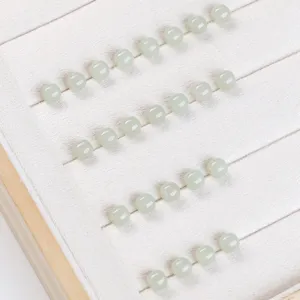 Close-up of natural Hetian jade square beads arranged in a white velvet jewelry tray slots