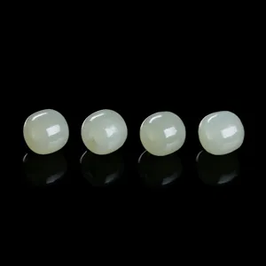 Macro detail of four natural Hetian jade celadon green loose beads on black background