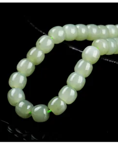 Macro detail of natural Hetian jade barrel beads with smooth translucent texture