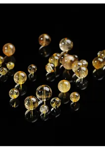 Makroansicht von naturreinen, goldfarbenen Rutilquarz-Kristallperlen für Schmuck.