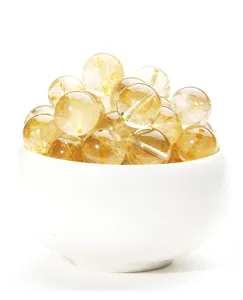 Makroansicht von natürlichen, goldfarbenen Rutilquarz-Kristallperlen in einer weißen Schale.