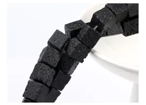 Macro view of natural black volcanic lava stone cube beads with porous textures.